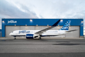 JetBlue a220 aircraft in front of a hangar with the JetBlue logo